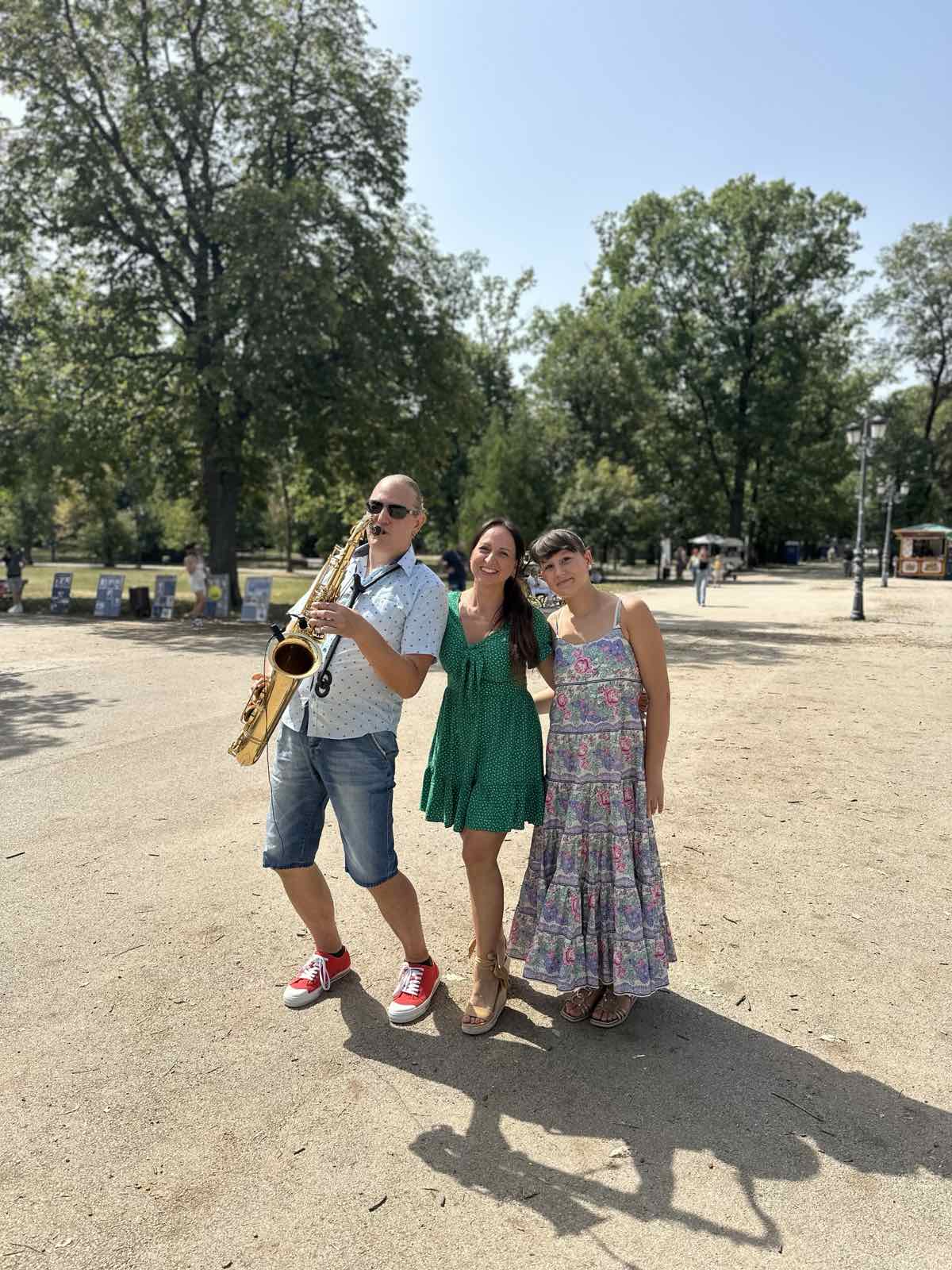 Музикант със саксофон и гостите на събитието по алеята в парка