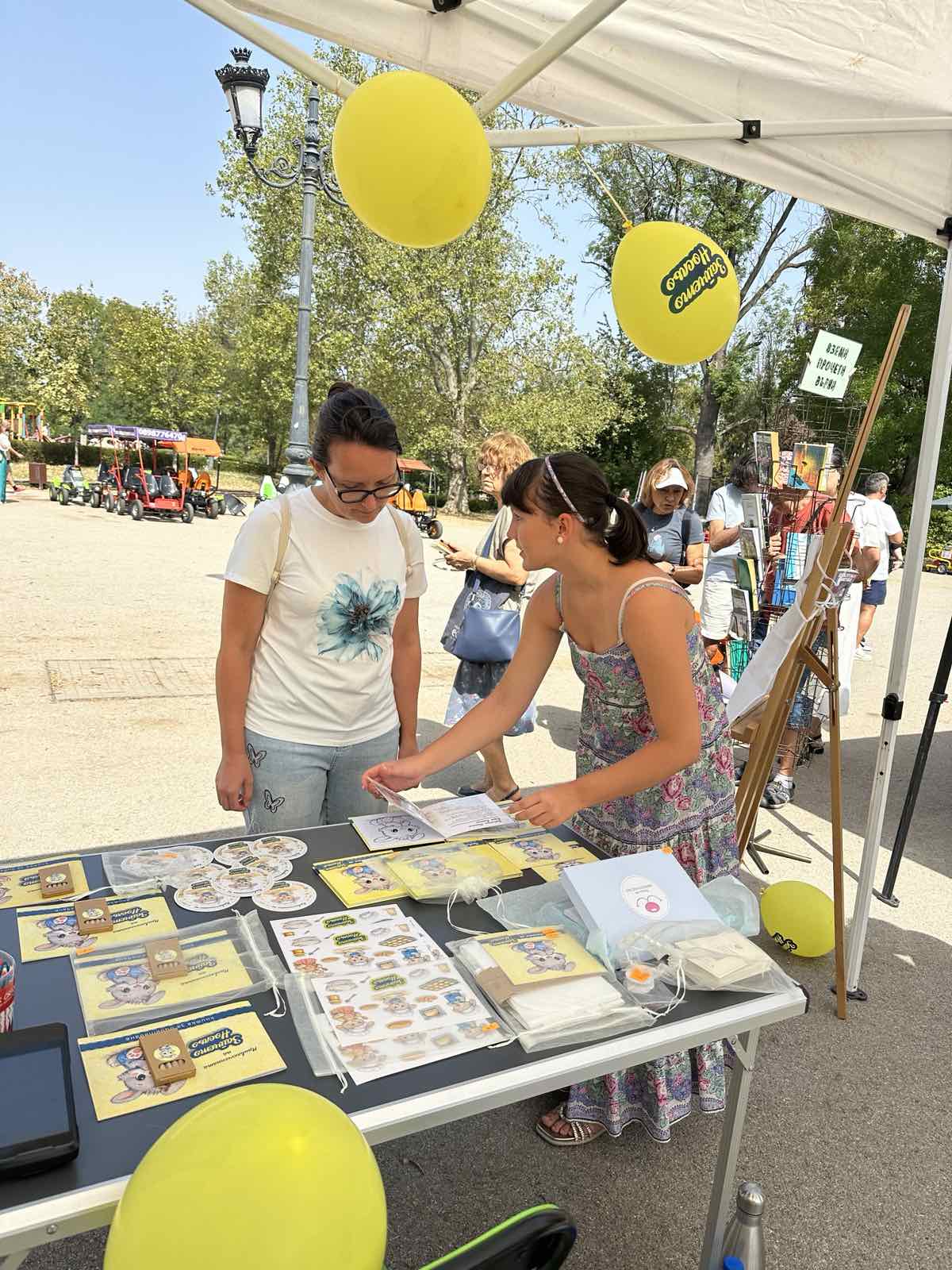 Гости разглеждат книжките и книжката за оцветяване на щанда